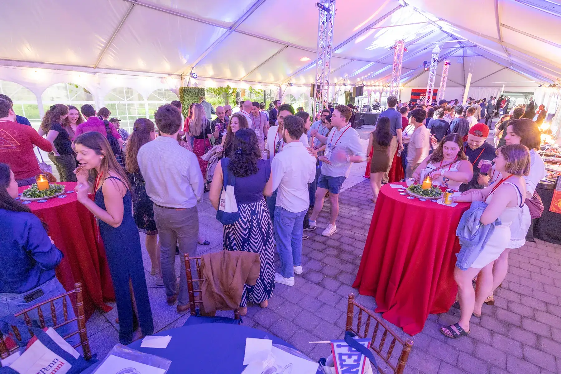 Penn alumni mingle around red cocktail tables inside a large illuminated event tent during Alumni Weekend 2026.