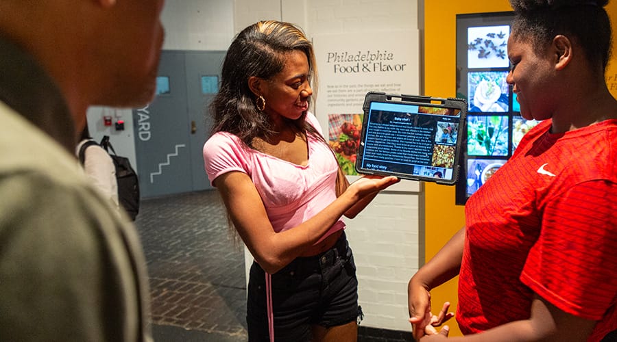 Two students offer a pop-up tour to a visitor in the Penn Museum's Ancient Food and Flavor exhibition