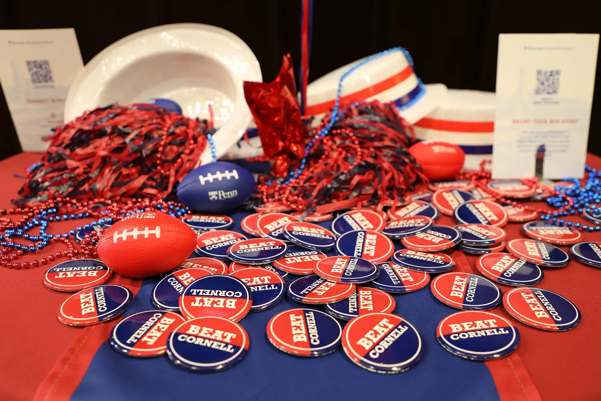Close-up of Penn-themed table with 'Beat Cornell' buttons and cheer gear