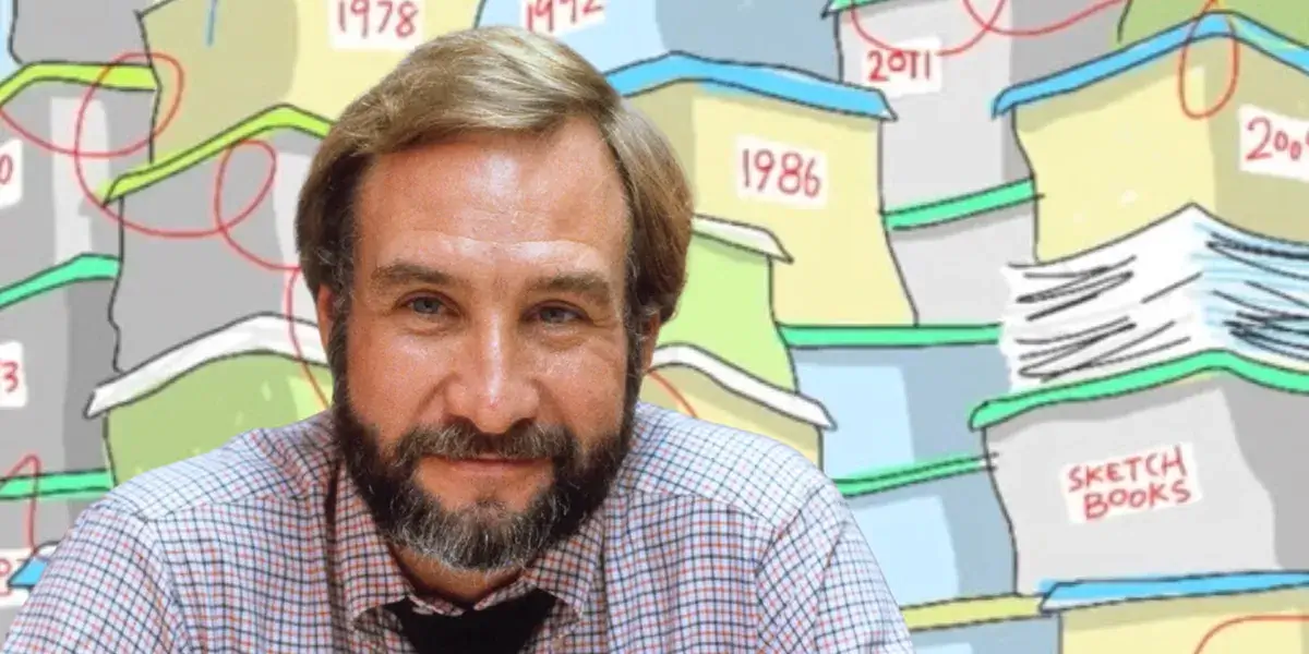 The late Tony Auth sits in front of an illustrated background showing stacks of sketchbooks and dated files.
