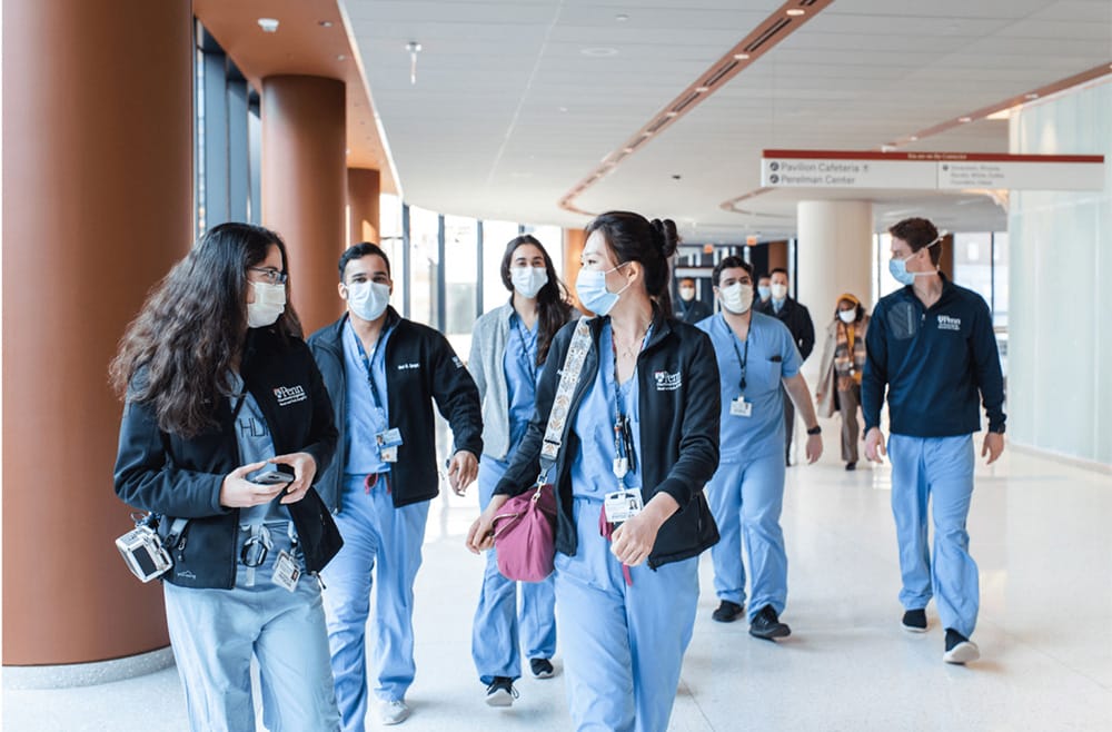 A group of students in the Perelman School of Medicine walk together down a hallway.