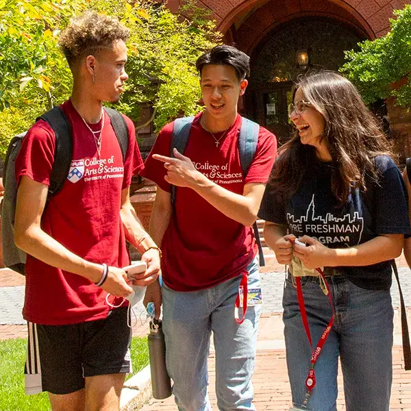 University of Pennsylvania students sharing a laugh in front of the iconic red-brick Fisher Fine Arts Library.