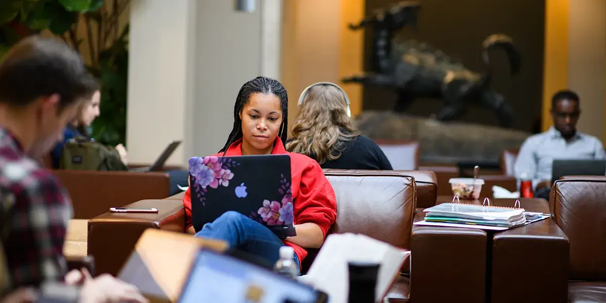 Students work on laptops in a law school lounge.