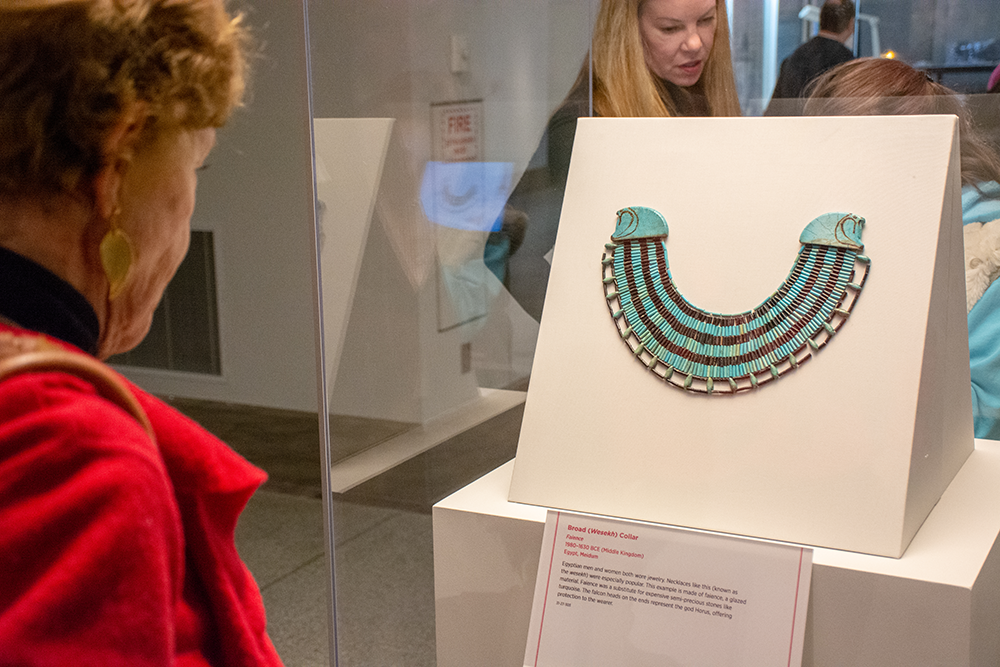 Missy McQuiston looks at a magnificent faience necklace on one side of the case, with Allison Weiss Brady, and her daughter on the other.
