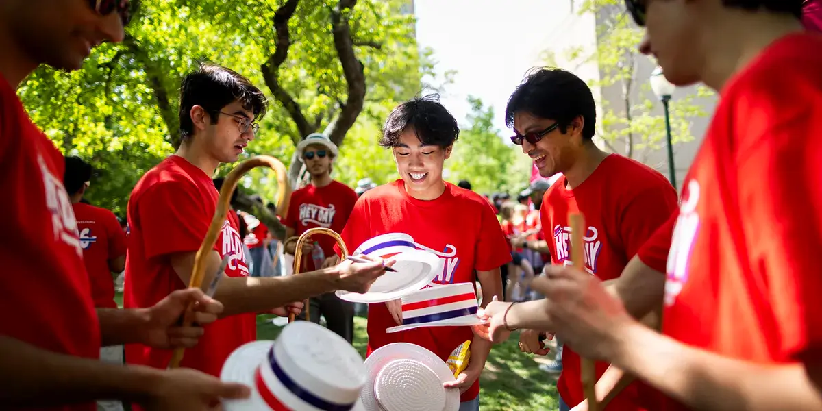 Students in red Penn shirts gather outdoors during a campus event.