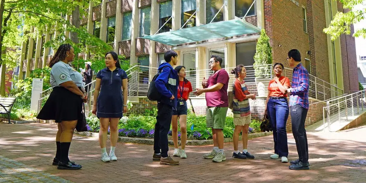 People talk in small groups outside Penn's School of Social Policy and Practice on a sunny day.